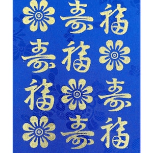 Pode incluir: Um tecido azul com flores bordadas em ouro e caracteres chineses. Os caracteres são "香" (xiang) que significa "fragrância" e "福" (fu) que significa "fortuna".