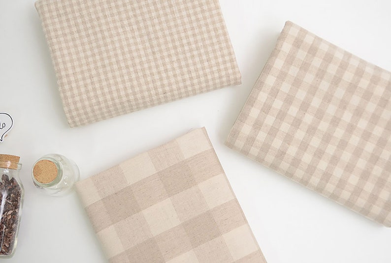 May include: Three pieces of beige and white gingham fabric with different sized checks.
