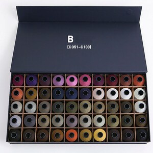 Puede incluir: Una caja negra con la tapa abierta, que revela una colecci&oacute;n de 50 carretes de hilo de varios colores. La caja est&aacute; etiquetada con "B [C 051 - C 100]".