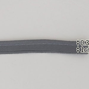 May include: Gray fabric trim with a stitched edge. The trim is 0.3 cm wide and 1 cm long.