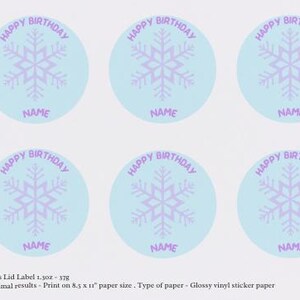 Pode incluir: Seis autocolantes redondos azuis claros com um floco de neve roxo. Cada autocolante tem as palavras "HAPPY BIRTHDAY" no topo e "NAME" na parte inferior. Para anivers&aacute;rios.
