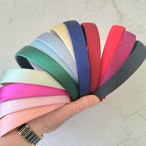 Puede incluir: Un conjunto de diez diademas de satén en varios colores, incluyendo negro, azul marino, rojo, burdeos, verde, azul claro, crema, rosa claro, rosa y verde claro.