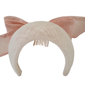 May include: A white headband with a pink bow on the side. The headband has a comb on the back for easy attachment.