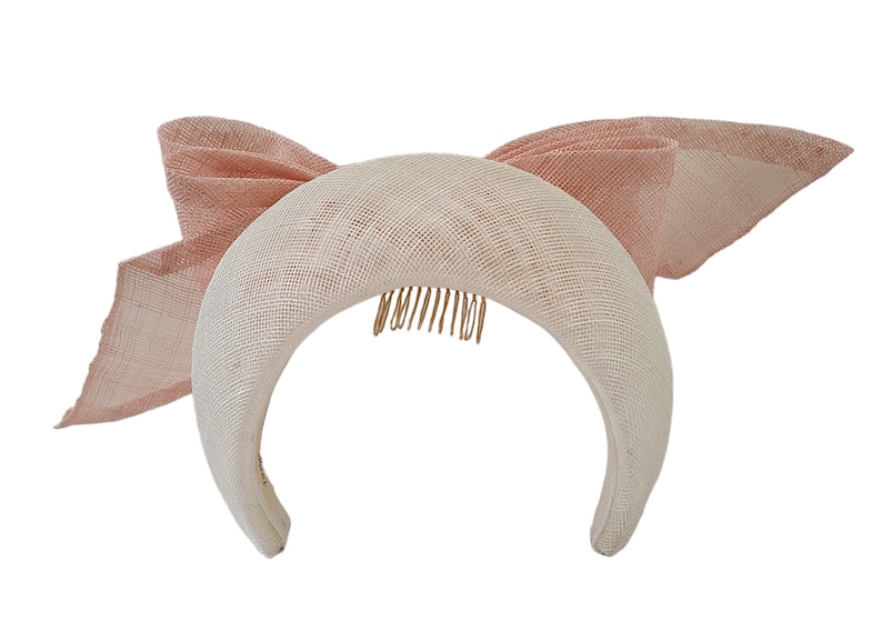 May include: A white headband with a pink bow on the side. The headband has a comb on the back for easy attachment.