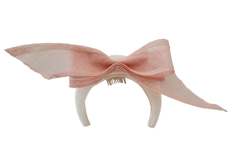 May include: A white headband with a large pink bow. The headband has a comb attached to the back.