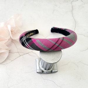 Può includere: Un cerchietto in tessuto a quadri rosa, grigio e nero con retro in velluto nero.