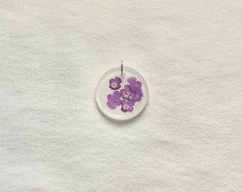 Pendentif en résine en forme de cercle blanc avec des fleurs de lantana violettes pressées