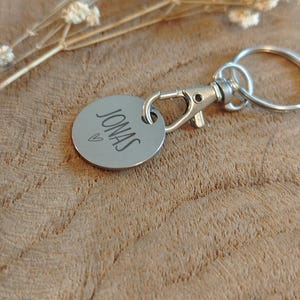 May include: A silver keychain with a round tag that says "JONAS" with a small heart symbol above the name.