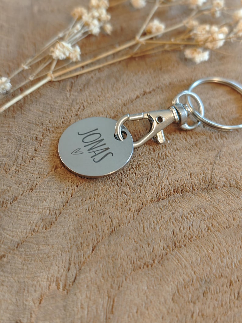 May include: A silver keychain with a round tag that says "JONAS" with a small heart symbol above the name.