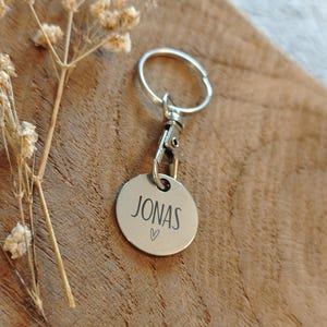 May include: Silver keychain with a round tag that says "JONAS" with a small heart symbol.