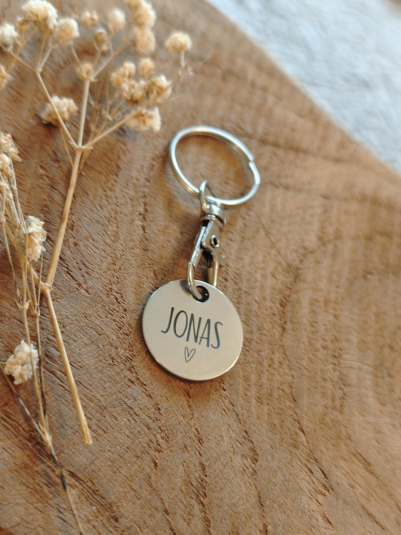 May include: Silver keychain with a round tag that says "JONAS" with a small heart symbol.