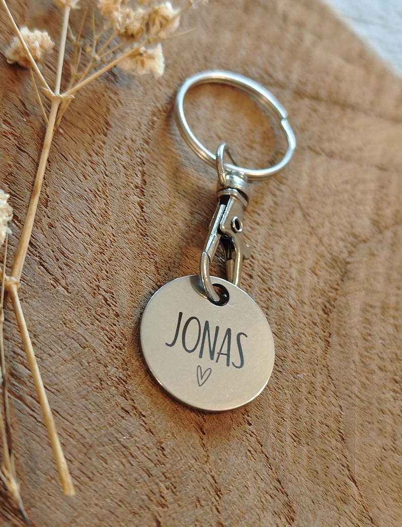 May include: Silver keychain with a round tag that says "JONAS" with a small heart symbol.