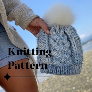 May include: A blue and white knitted beanie with a white pom pom. The beanie has a cable knit pattern. The text "Knitting Pattern" is visible in the image.