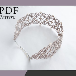 May include: A delicate, grey crocheted choker necklace with white beads. The necklace is made of a fine, intricate pattern and is a beautiful piece of jewellery.