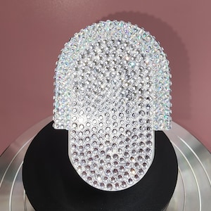 May include: A white, hand-shaped object covered in iridescent rhinestones.