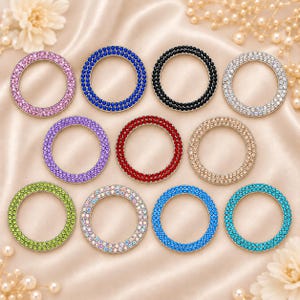 May include: A collection of eleven circular rings, each featuring a double row of small, uniform rhinestones. The rings are presented in a variety of colors including pink, dark blue, black, clear, purple, red, beige, lime green, iridescent, and teal.