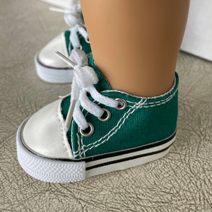 May include: Green canvas high-top sneakers with white laces and a white rubber sole. The shoes have a black stripe around the sole.