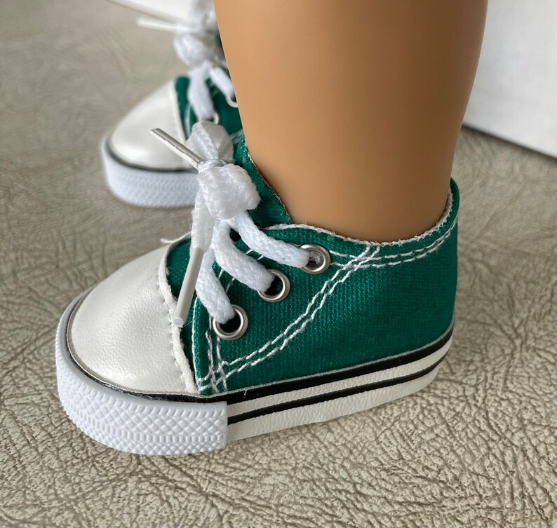 May include: Green canvas high-top sneakers with white laces and a white rubber sole. The shoes have a black stripe around the sole.