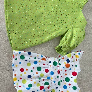 May include: Two dresses, one with a green background and small multi-coloured polka dots, and the other with a white background and large multi-coloured polka dots.