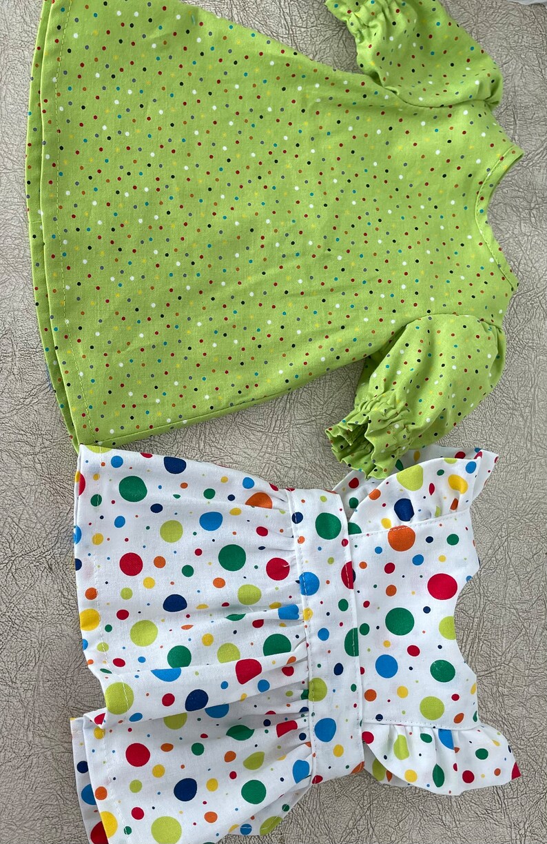 May include: Two dresses, one with a green background and small multi-coloured polka dots, and the other with a white background and large multi-coloured polka dots.