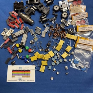 May include: A collection of assorted electronic components including integrated circuits, capacitors, resistors, connectors, and metal oxide varistors in labeled plastic bags. A small white card with a resistor color code chart is included.