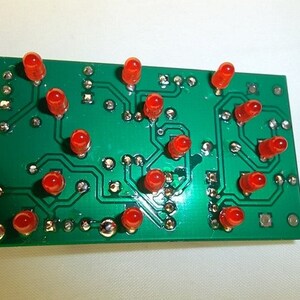 May include: A green circuit board with 13 red LEDs soldered to it. The LEDs are arranged in a pattern.