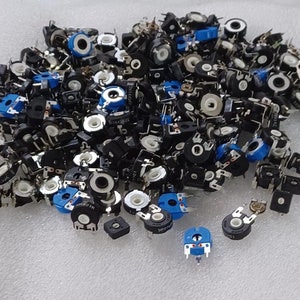 May include: A large pile of small, round, black potentiometers with blue and white accents. The potentiometers are used for adjusting electrical resistance.