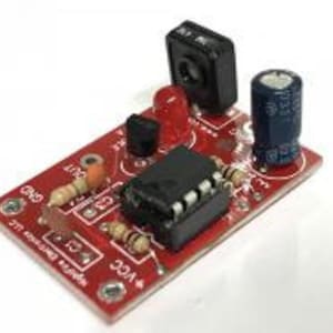 May include: A red circuit board with a small red LED, a black sensor, a black integrated circuit, and a blue capacitor. The board has the text "GND", "OUT", "3.3V", and "220 Ohm" printed on it.