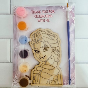 May include: A paint-your-own kit featuring a wooden cutout of a cartoon character, paint pots in pink, orange, blue, purple, yellow, and brown, and a paintbrush. The kit is packaged with a card that reads, "Thank you for celebrating with me."