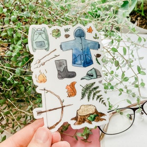 K&ouml;nnte beinhalten: Ein Stickerbogen mit Aquarellillustrationen von Camping- und Outdoor-Abenteuer-Elementen. Enth&auml;lt einen Rucksack, einen blauen Regenmantel, ein Lagerfeuer, einen Pfeil und Bogen, ein Eichh&ouml;rnchen und einen Baumstumpf.