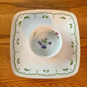 May include: A white square serving dish with a scalloped edge and a green floral design. A smaller white bowl with a floral design sits inside the dish.
