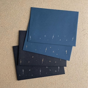 May include: Four envelopes with a starry night design. Two are dark blue and two are black with gold and white stars.