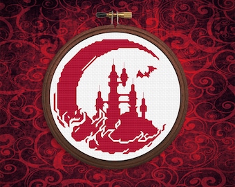 May include: A red and white cross-stitch embroidery hoop with a red silhouette of a castle and a bat flying above it. The castle is set against a red crescent moon.