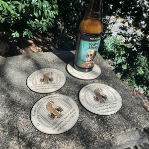 May include: A bottle of Voodoo Ranger Imperial IPA beer rests on a coaster. Three additional coasters with text and a cartoon illustration of a creature behind bars are visible. The coasters have text that reads "Facebook Fact Repeat Offenders", "Community Standards!", and "Fact checking for safety".