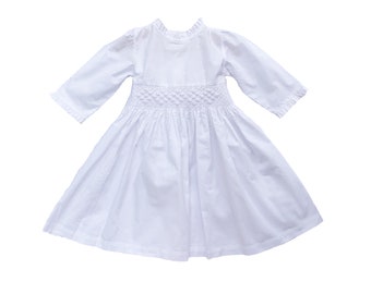 May include: A white long-sleeved dress with a smocked bodice and a full skirt.