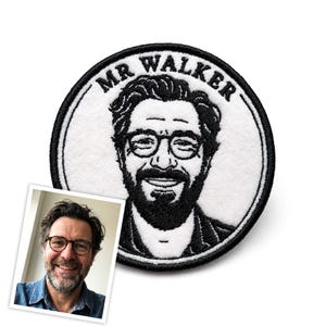 May include: A circular embroidered patch featuring a black and white portrait of a person with a beard and glasses. The text MR WALKER is stitched in black along the top edge of the white circular background, which is framed by a thick black border.