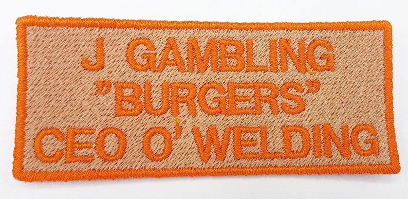 a patch with the text "J GAMBLING "BURGERS" CEO O'WELLING" embroidered on it.