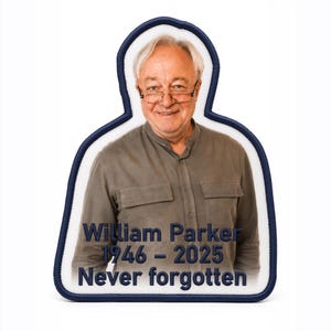 May include: Embroidered patch featuring a smiling man with glasses, framed by a white border and a navy blue stitched edge. The patch includes the text "William Parker 1946-2025 Never forgotten" in navy blue thread. The man is wearing a gray shirt.