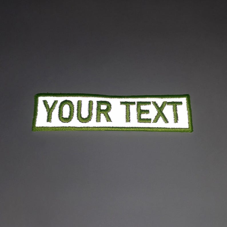 A rectangular patch with the text "YOUR TEXT" printed on it in green.