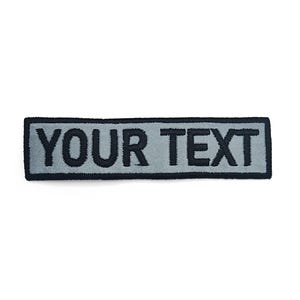 A gray rectangular patch with the text "YOUR TEXT" printed on it.