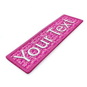 Op de afbeelding: Roze camouflage stoffen patch met witte tekst die "Your Text" zegt.