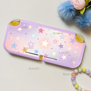 May include: A lavender handheld gaming console case featuring a gradient background with scattered multi-colored stars and small hearts. The text BestABC is printed multiple times across the surface. The case has yellow accents on the top corners.