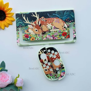 May include: A protective console cover and two controller skins featuring a printed illustration of a deer resting in a vibrant meadow filled with colorful flowers, mushrooms, and green foliage. The text BestABC is visible on the surface.