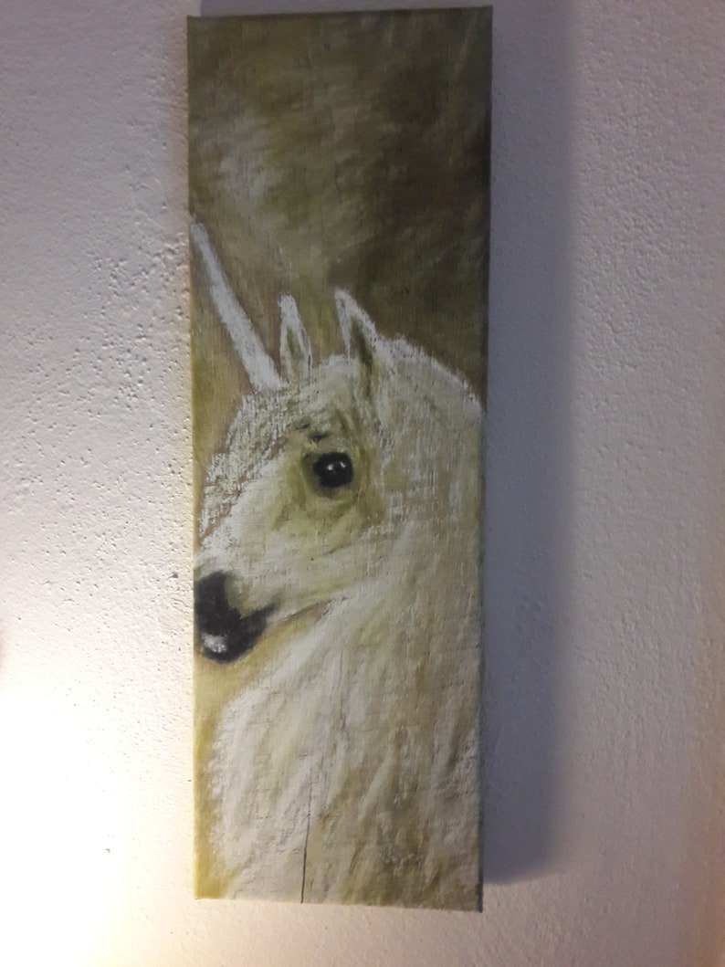 Op de afbeelding: Een close-up van een schilderij van een wit eenhoornhoofd met een lange, spiraalvormige hoorn. De achtergrond is in gedempte bruin- en groentinten.