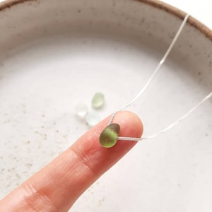 Puede incluir: Un delicado collar de cadena de plata con un solo colgante de vidrio de mar verde claro.