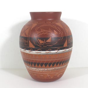 May include: A brown ceramic vase with a geometric design and a fish motif. The vase is decorated with black, white and brown paint.