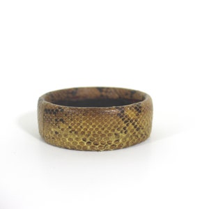May include: A brown and gold snakeskin bracelet with a textured pattern.