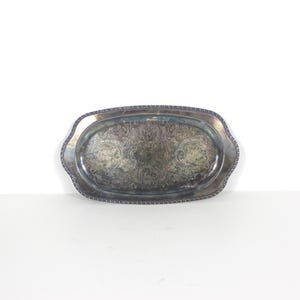May include: An antique silver-plated serving tray, oval in shape, with intricate floral and scrollwork. The tray features a beaded edge and a gently scalloped rim. A vintage piece, suitable for serving or display purposes.