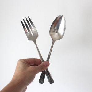 May include: A silver serving set with a fork and spoon. The fork has a decorative design and the spoon has a rounded bowl.