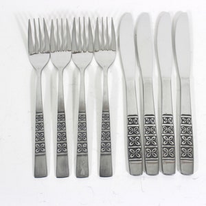 May include: Set of eight stainless steel flatware, including four forks and four butter knives. The handles feature a repeating geometric pattern.